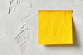 Bright yellow sticky note on textured white wall adds a pop of color for notes and reminders Royalty Free Stock Photo