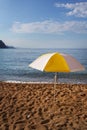 Bright yellow striped beach umbrella against the blue sky. Beach vacation concept. Place for an inscription Royalty Free Stock Photo