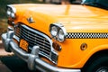 Bright yellow taxicab parked in a city street with a retro look