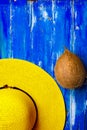 Bright yellow women`s straw hat whole coconut on old painted plank wood blue background. Summer beach vacation Royalty Free Stock Photo