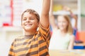 Bright young minds with all the answers. Smiling young boy in class raising his hand confidently to answer a question - Royalty Free Stock Photo