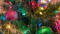 Brightly colored, cheery Christmas tree ornaments hung up with lights and tinsel Royalty Free Stock Photo