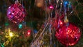 Brightly colored, cheery Christmas tree ornaments hung up with lights and tinsel Royalty Free Stock Photo