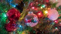 Brightly colored, cheery Christmas tree ornaments hung up with lights and tinsel Royalty Free Stock Photo