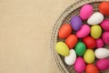 Brightly colored easter eggs, in a straw basket against a beige background Royalty Free Stock Photo