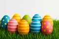 Brightly colored Easter eggs with various patterns, including stripes and polka dots, are arranged on vibrant green grass Royalty Free Stock Photo