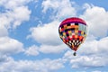 Brightly colored hot air balloon ascending against a vibrant cloudy blue sky