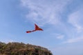 Brightly colored kite with a dragon head and wide wings flies under a sky-blue sky with a delicate white cloud haze. Toy. Royalty Free Stock Photo