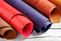 Brightly colored leather in rolls on the wooden background. Leather craft.