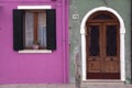 Brightly coloured pink and green house wall in Burano where houses with shutters and doors are painted in beautiful colours Burano