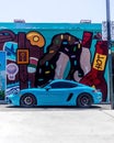 From old to new, Porsche sports cars parked near an art mural in a downtown art Miami district.