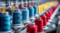 Brightly colored sewing thread spools arranged in a row on an industrial textile manufacturing machine, showcasing vibrant red, Royalty Free Stock Photo