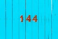 House number 144 on a turquoise wooden gate worn and with cracks Royalty Free Stock Photo