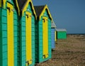 Brightly colored Turquoise & yellow beach huts. Deep Blue sky, pebble beach.