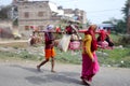 Brightly dressed religious pilgrims walk alongside the road in rural India.