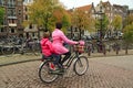 A woman on a bicycle, carrying her child on the rear child seat. Amsterdam, Netherlands