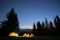 Brightly illuminated camping tents glowing on campsite in dark mountains under night stars covered sky. Active lifestyle Royalty Free Stock Photo