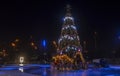 A brightly illuminated ice rink with Christmas tree with decorations on the center