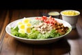 brightly lit cobb salad on a dark wooden table