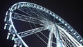 Brightly lit ferris wheel ride, which spinning at night or evening carnival. Low angle. Colored lights flashing. Concept Royalty Free Stock Photo