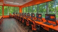 A brightly lit modern computer lab with large windows showcasing lush green trees outside Royalty Free Stock Photo