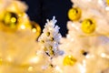 Brightly lit white artificial Christmas trees at night. Golden balls covered with drops of water, and garlands hanging on white Royalty Free Stock Photo