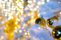 Brightly lit white artificial Christmas trees at night. Golden balls covered with drops of water, and garlands hanging on white Royalty Free Stock Photo