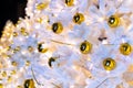 Brightly lit white artificial Christmas trees at night. Golden balls covered with drops of water, and garlands hanging on white Royalty Free Stock Photo