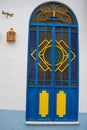 Brightly painted window in Alte, Portugal, in blue and yellow colors against a white building facade