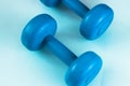 Brightly turquoise dumbbells on a blue background