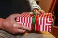 Brightly wrapped Christmas present in hands of older man - closeup and selective focus Royalty Free Stock Photo