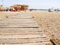 Plank walkway leading to carousel across pebble beach at Brighton