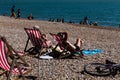 Brighton, UK - June 2018 Couple Relaxing on Wood Adjustable Recliner under the Sun. Family and Group Enjoying Blue Water