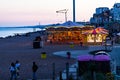 Brighton, UK - June 2018 People Relaxing on the Pebbled Sand of Brighton Beach in England. Kids Riding the Carousel in