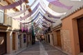 BRIHUEGA, SPAIN - JULY 10, 2021: Narrow ancient town street covered with purple shaders during lavender fields blooming period,