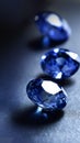 Brilliant blue gemstones on a dark surface, their faceted cuts casting reflections and showcasing their deep, rich color