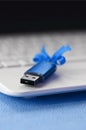 Brilliant blue usb flash memory card with a blue bow lies on a blanket of soft and furry light blue fleece fabric beside to a whit