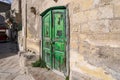 A brilliant, bright green, weathered wooden doorway into a stone building in the ancient city of Matera Italy, in the Basilicata