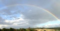 Rainbow across blue sky over green hills Royalty Free Stock Photo