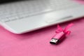 Brilliant pink usb flash memory card with a pink bow lies on a blanket of soft and furry light pink fleece fabric beside to a whi