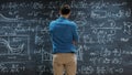 Brilliant Young Mathematician Approaches Big Blackboard and Thinks about Solving Long and Complex Royalty Free Stock Photo
