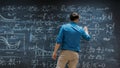 Brilliant Young Mathematician Is Writing on Big Blackboard and Thinking about Solving Long and Royalty Free Stock Photo
