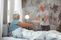 Smiling husband bringing breakfast to the bed of his wife. Royalty Free Stock Photo