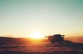 Bringing in a golden harvest. a combine harvester working in a field at sunset. Royalty Free Stock Photo