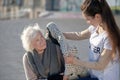 Helpful volunteer bringing warm coat for homeless woman