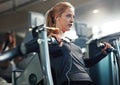 She brings her best effort to every workout. a young woman working out with a chest press at a gym.