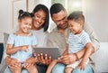 Brining us closer in a world of ruin. a young family happily bonding while using a digital tablet together on the sofa