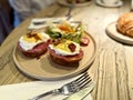 Brioche with poached egg and ham served at restaurant on wooden table Royalty Free Stock Photo