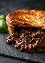 British beef steak pie with onion, wine gravy on rustic stone board Royalty Free Stock Photo