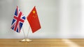 British and Chinese flag pair on a desk over defocused background